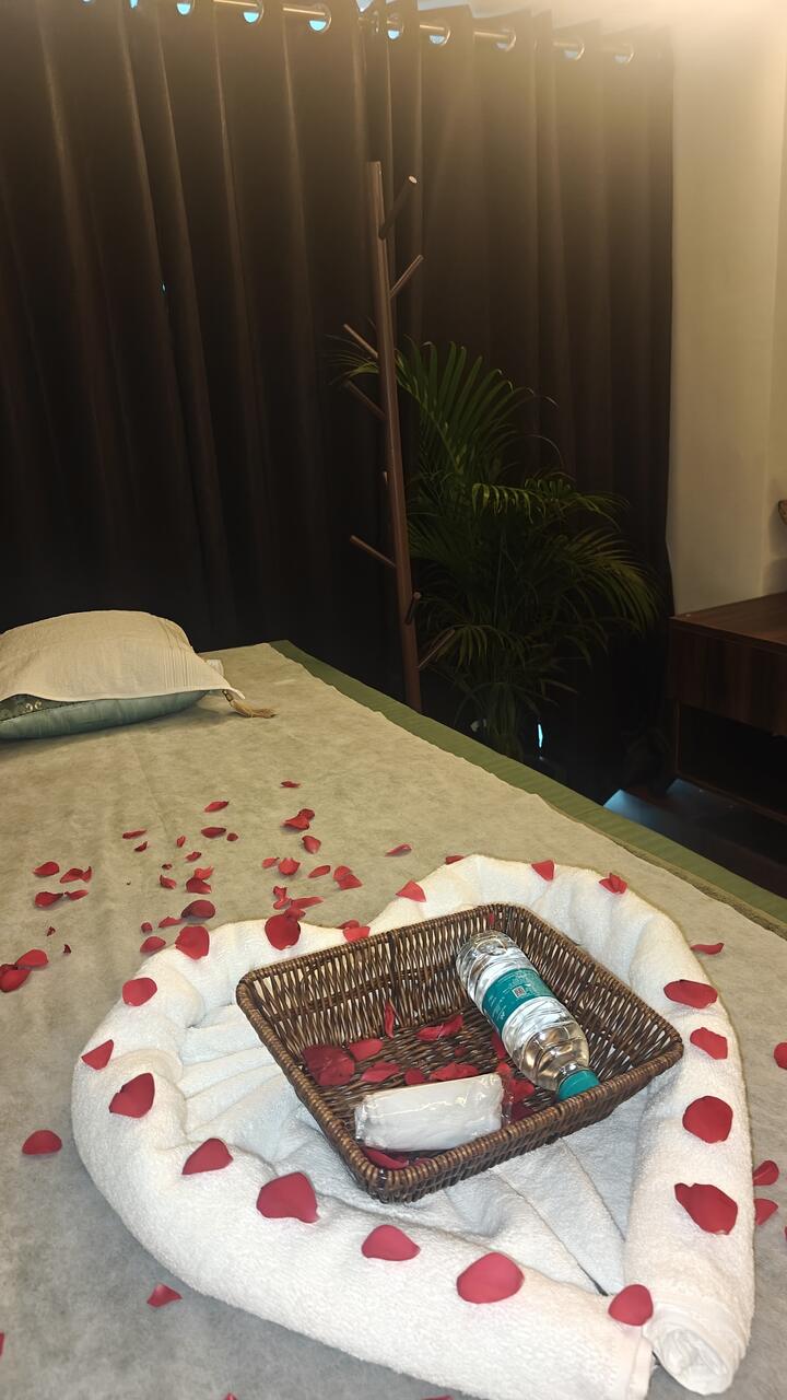 A towel folded into a heart, ringed with rose petals, on one of the two beds