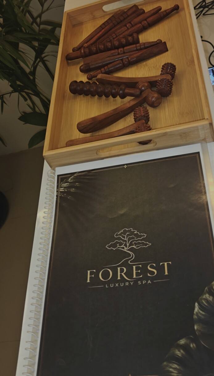 A bamboo tray of carved wooden therapy sticks resting on the spa's own menu, its tree mark printed in gold on dark green